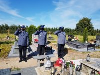 Komendant Powiatowy Policji w Kutnie wraz z dwoma innymi policjantami oddają honor przy grobie poległego policjanta