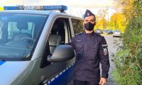 Policjant stoi przy radiowozie. Radiowóz zaparkowany jest na dziedzińcu Komendy Powiatowej Policji w Kutnie