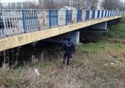 Policjant wchodzi pod most skontrolować czy nie przebywają tam bezdomni, obok płynie rzeka