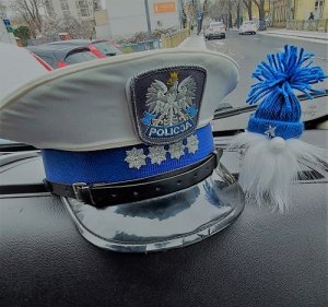 czapka policyjna ruchu drogowego leży w samochodzie obok skrzat zrobiony z szyszki