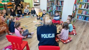 policjantka siedzi na krzesełku dzieci siedzą w kółku na podłodze