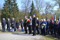 Komendant Powiatowy Policji w Kutnie stoi w kolejce do złożenia kwiatów pod pomnikiem wraz z delegacją ze Straży Pożarnej