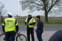 Policjanci kontrolują rowerzystę, obok redaktor radia Q w ramach wspólnych działań &quot;Bezpieczny rowerzysta&quot;