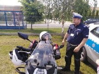 motocykl nieoznakowany, na nim siedzi dziecko przymierza kasak, obok stoi policjant