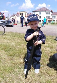 dziecko ubrane w mundur policyjny trzyma pałkę służbową