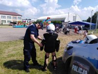 policjant ubiera dziecko w kamizelkę, kask i ochraniacze