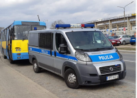 autobus, przed nim stoi radiowóz oznakowany