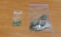 na stole leżą dwie torebki foliowe z zapięciem strunowym, w środku susz roślinny - marihuana