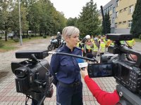 policjantka udziela wywiadu do telewizji, widać kamery w tle motocykle policyjne i uczniowie w kamizelkach odblaskowych