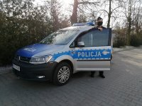 radiowóz policyjny przy otwartych drzwiach stoi policjant