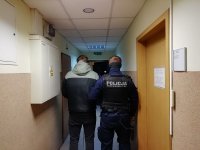 korytarz jednostki, policjant umundurowany prowadzi zatrzymanego.