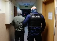 korytarz jednostki, policjant umundurowany prowadzi zatrzymanego.