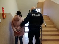 korytarz jednostki, policjant umundurowany prowadzi zatrzymanego.