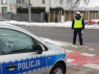 policja z Ruchu Drogowego stoi przy drodze, na pierwszy planie widać kawałek radiowozu policyjnego