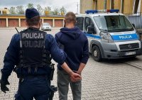 dziedzinie KPP Kutno, policjant prowadzi zatrzymanego do radiowozu