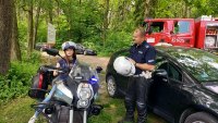 las, motocykl policyjny nieoznakowany, na motocyklu w czapce policyjnej siedzi dziewczynka, obok policjant