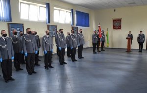 sala odpraw mianowani policjanci stoją w szeregu na wprost lektor stoi przy mównicy obok mistrz ceremonii