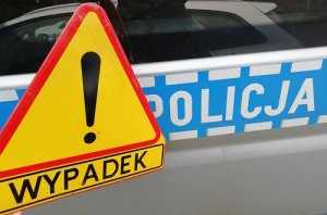 napis Policja na niebieskim tle na nim trójkąt żółty z wykrzyknikiem, pod spodem napis wypadek