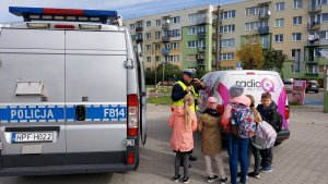 parking przed szkoła policjant rozdaje odblaski,
