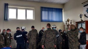 sala odpraw w KPP Kutno, uczniowie szkoły mundurowej przymierzają sprzęt policyjny, tarcze pałki, kaski