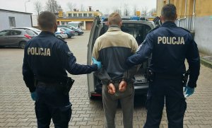 policjanci stoją z zatrzymanym mężczyzną