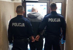 policjanci stoją z zatrzymanym mężczyzną