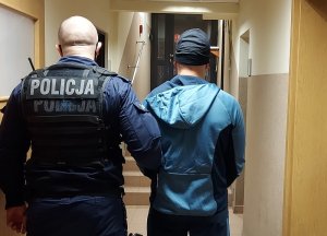policjant prowadzi korytarzem zatrzymanego