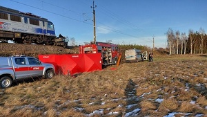 pole, tory , na torach pociąg, przed nim zmiażdżony samochód, pod nasypem straż pożarna policja pogotowie