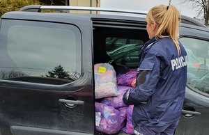 policjantka wynosi paczki z darami z samochodu