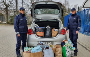 radiowóz otwarty bagażnik w nim paczki z darami, obok stoją policjantki