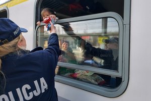 policjantka podaje przez okno w wagonie maskotke