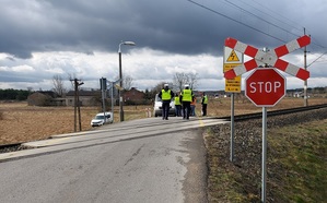 znak stop przed przejazdem kolejowym za torami policjant , funkcjonariusze SOK rozmawiają z kierowca samochodu