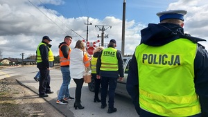 policjant i funkcjonariusze SOK rozmawiają z kierowca samochodu, który zatrzymał się prze przejazdem kolejowym