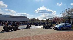 parking na środku mata , uczniowie szykują sie do pokazu, z tyłu widownia