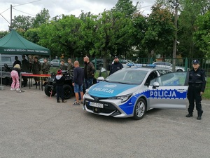 plac przed budynkiem uczelni, radiowóz stoi obok niego policjanci, z lewej strony namiot Brygady Obrony Terytorialnej z pokazem sprzętu, obok radiowozu stoi quad