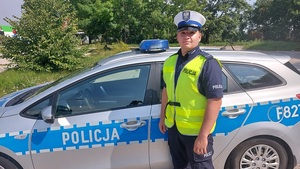 policjant stoi przy radiowozie