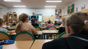 klasa, dzieci siedzą w ławkach, policjantka stoi przodem do dzieci