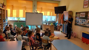 klasa, dzieci siedzą na podłodze, policjantka prowadzi zajęcia