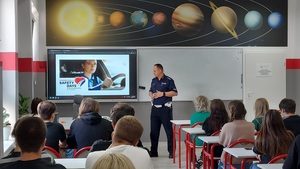 klasa lekcyjna policjant prowadzi prelekcje, uczniowie siedzą w klasie na krzesłach.