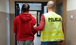 policjant prowadzi zatrzymanego korytarzem