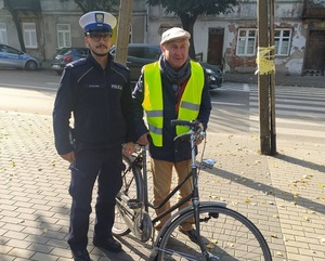 policjant ruchu drogowego obok stoi pan z rowerem w kamizelce odblaskowej