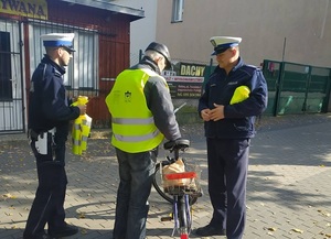 dwóch policjantów stoi na chodniku pan zakłada kamizelkę odblaskową