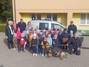 zdjęcie grupowe dzieci na zdjęciu widać pieska służbowego i policjantów stojących z tyłu