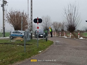 Funkcjonariusze policji i straży ochrony kolei wsólnie kontrolują pojazd przed przejazdem kolejowym.