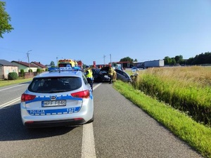 funkcjonariusze wykonują swoje czynności na miejscu zdarzenia, w tle dwa zderzone samochody.