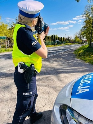 policjantka kontrolująca prędkość pojazdów na drodze.