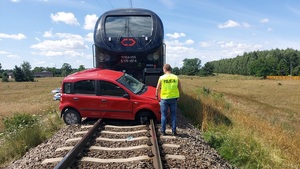 POLICJANT WYKONYJĄCY CZYNNOŚCI NA MIEJSCU ZDARZENIA SAMOCHODU OSOBOWEGO Z POCIĄGIEM.