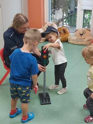 policjantka pokazuje dzieciom sygnalizator świetlny.