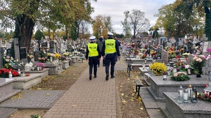 policjanci patrolujący teren cmentarza miejskiego.