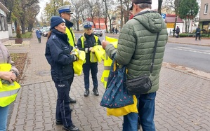 Policjanci rozdają kamizelki odblaskowe osobom pieszym w Kutnie.